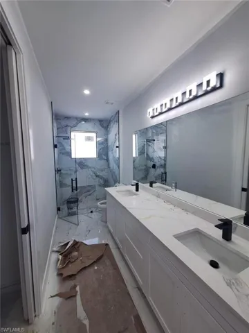 Bathroom featuring toilet, walk in shower, and vanity