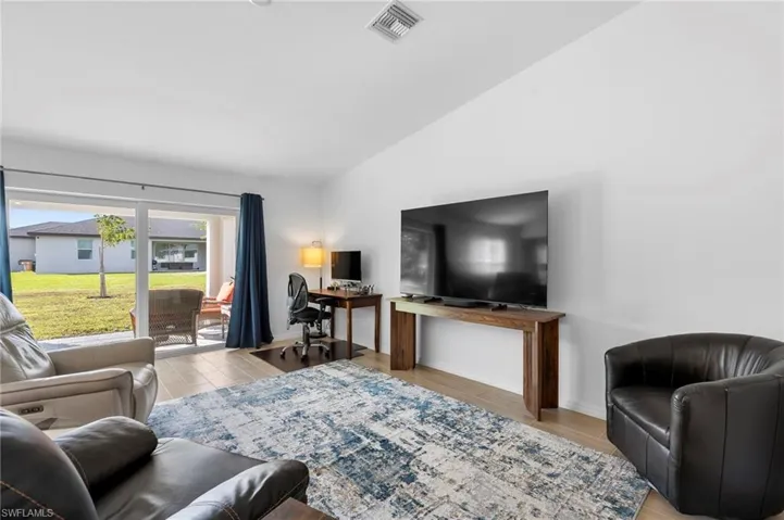 Living room featuring wood finish floors, a desk, and vaulted ceiling