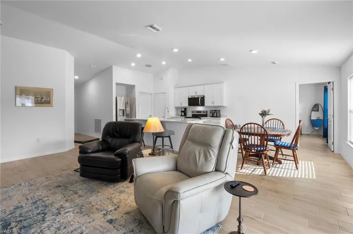 Living area featuring light wood-style floors, vaulted ceiling, and recessed lighting