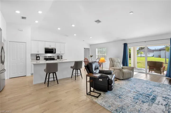 Living area with vaulted ceiling, light wood-type flooring, and recessed lighting