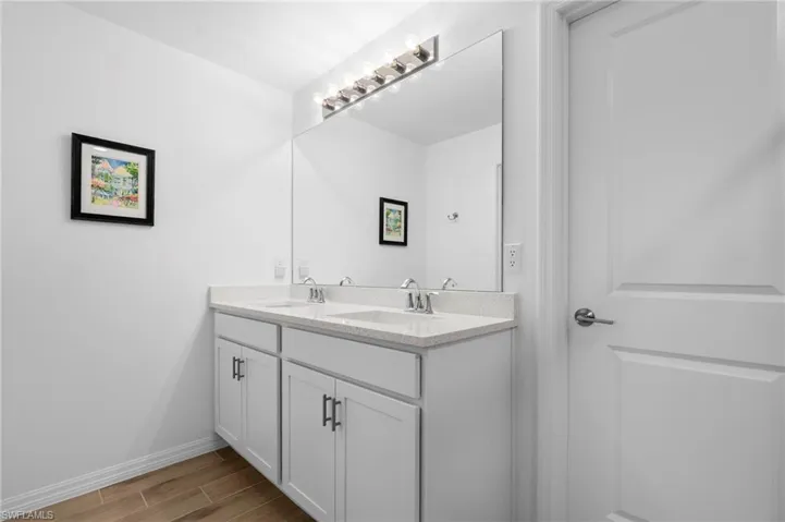 Full bathroom featuring double vanity and wood finish floors