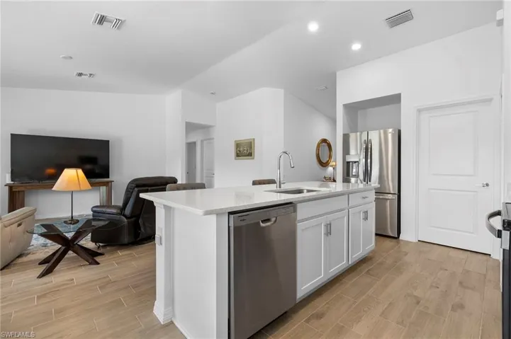 Kitchen featuring appliances with stainless steel finishes, wood tiled floors, open floor plan, white cabinetry, and recessed lighting