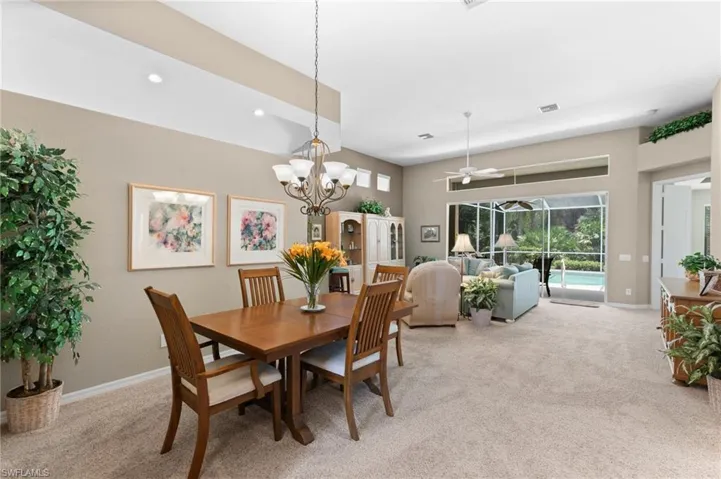 Dining space featuring ceiling fan with notable chandelier and carpet floors