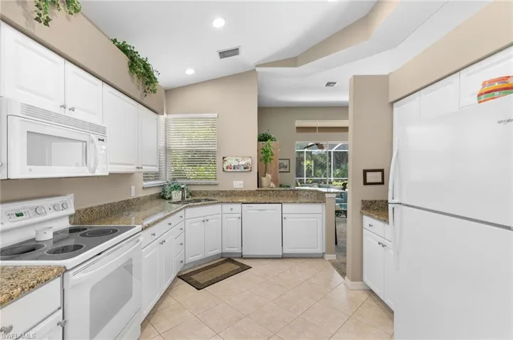 Kitchen featuring sink, light tile flooring, white appliances, and white cabinetry