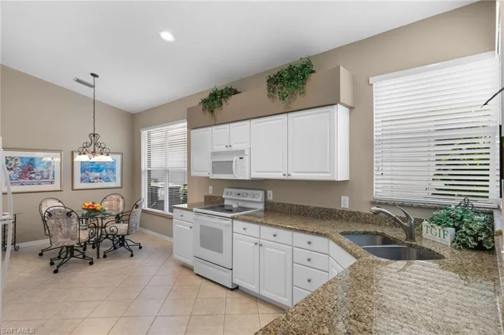 Kitchen with decorative light fixtures, sink, white cabinets, and white appliances