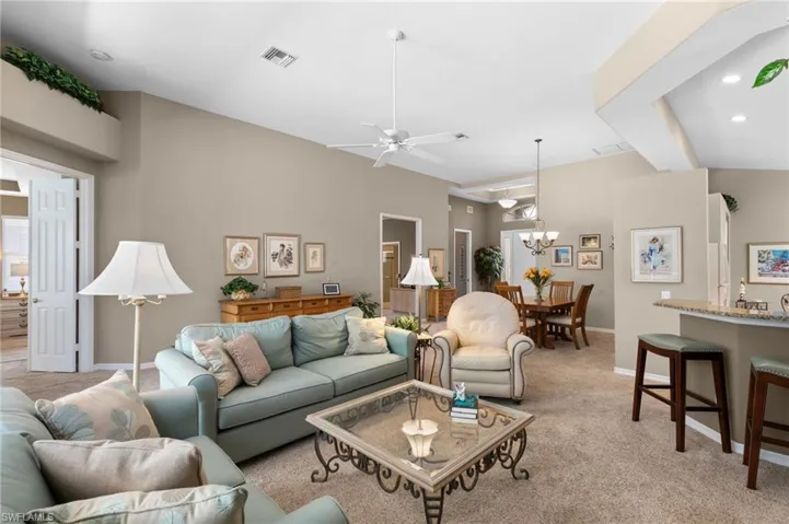 Living room with light colored carpet and ceiling fan with notable chandelier