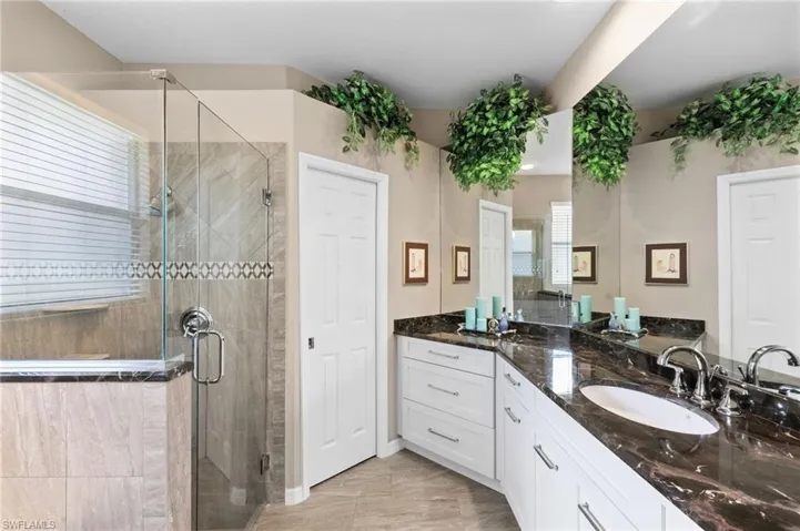 Bathroom featuring dual vanity, a shower with door, and tile flooring