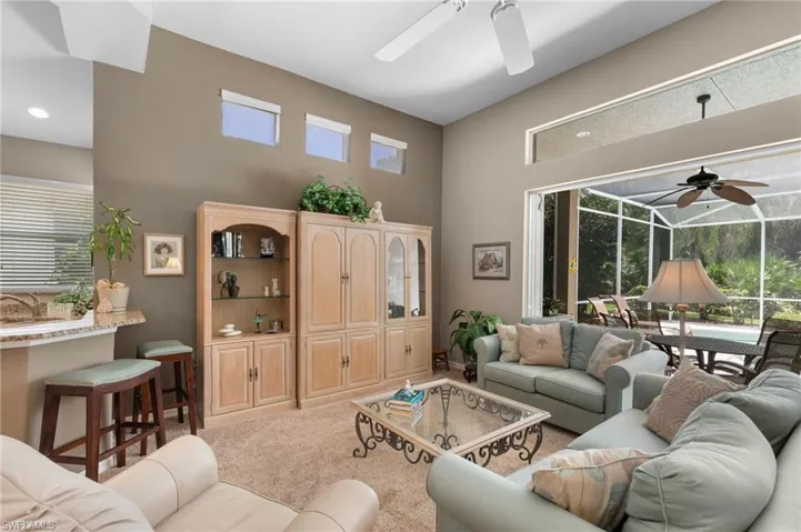 Living room featuring light colored carpet, a high ceiling, and ceiling fan