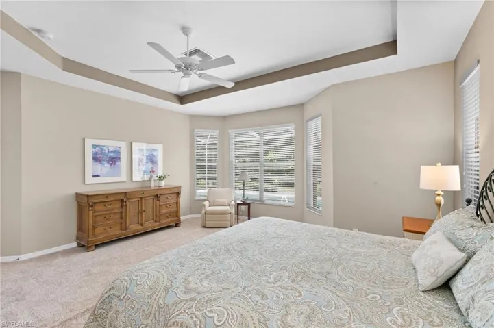 Bedroom with ceiling fan, a raised ceiling, and carpet flooring