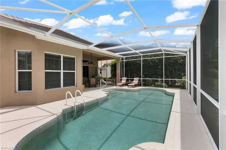 View of pool featuring glass enclosure, a patio area, and ceiling fan