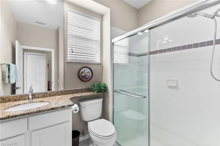 Bathroom with a shower with door, vanity, and toilet