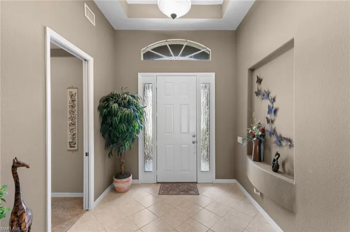 Tiled entrance foyer featuring a tray ceiling