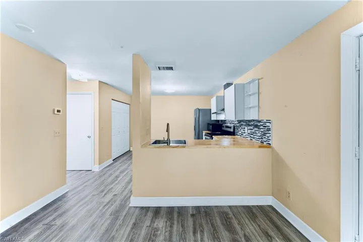 Kitchen featuring stainless steel electric range oven, freestanding refrigerator, wood finished floors, tasteful backsplash, and a peninsula