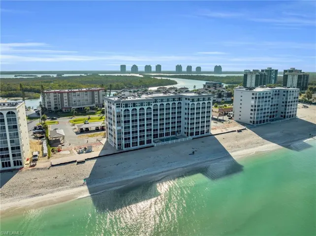 Beachfront multi-story building featuring arched window details, a flat roofline, and direct beach access
