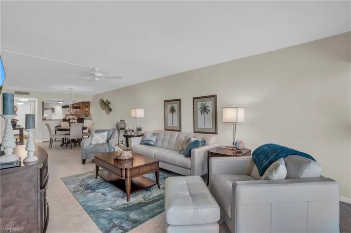Open-concept living space featuring neutral wall tones, tile flooring, a dining area with a chandelier, and a ceiling fan