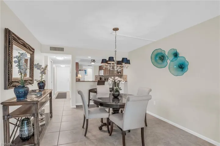 Dining area featuring tiled flooring, a decorative ceiling fixture, and a pass-through opening to an additional space