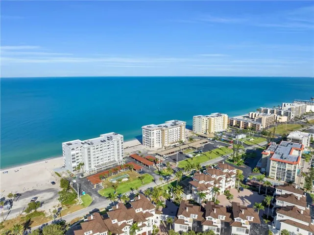 Expansive coastline featuring a sandy beach, clear blue water, and multiple waterfront residential buildings