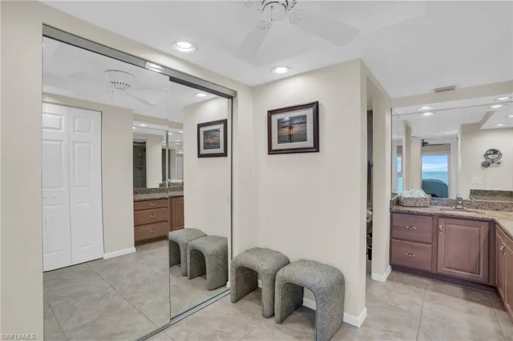Mirrored wardrobe doors reflecting a ceiling fan, recessed lighting, and tile flooring