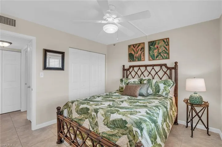 Bedroom featuring a decorative headboard, neutral wall paint, and a built-in ceiling fan with integrated lighting