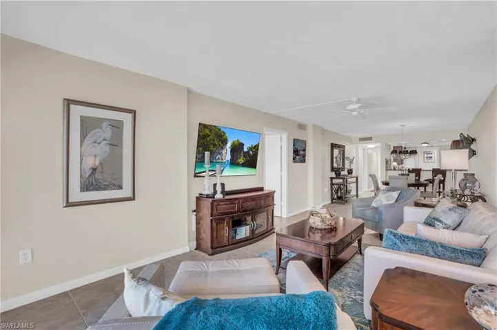Spacious living area featuring neutral wall tones, tile flooring, and ceiling fan