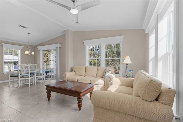 Tiled living room featuring crown molding, a wealth of natural light, lofted ceiling, and ceiling fan