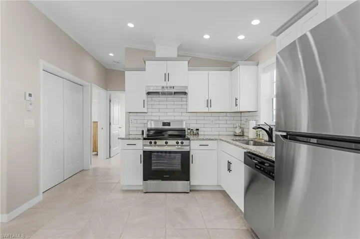 Kitchen featuring granite countertops, white cabinets, appliances with stainless steel finishes, and sink