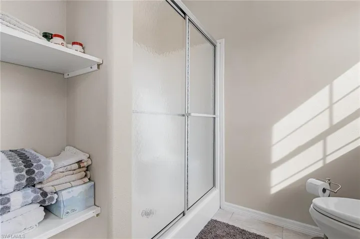 Bathroom with toilet, tile floors, and a shower with door