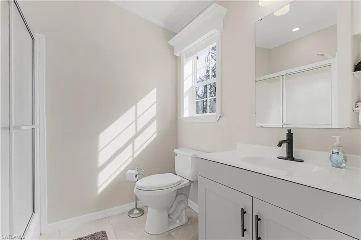 Bathroom featuring toilet, tile, walk in shower, ornamental molding, and vanity