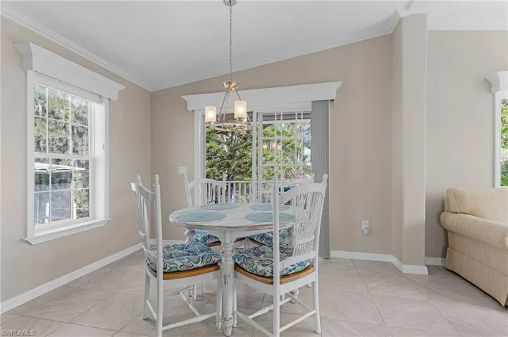 Tiled dining area with crown molding, lofted ceiling