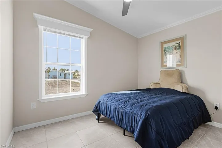 Tiled bedroom featuring ceiling fan, and crown molding