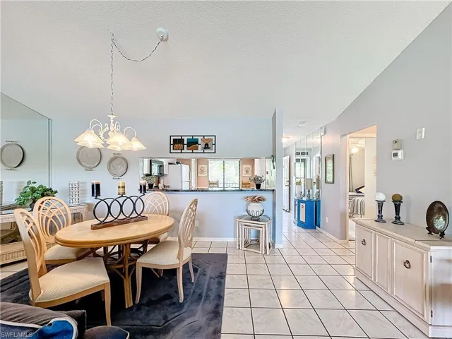 Dining room featuring a notable chandelier, a textured ceiling, lofted ceiling, and light tile floors
