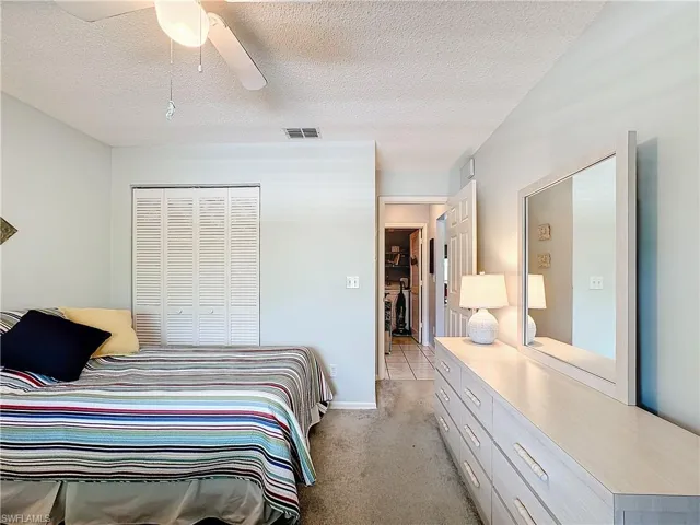 Carpeted bedroom featuring a textured ceiling, a closet, and ceiling fan