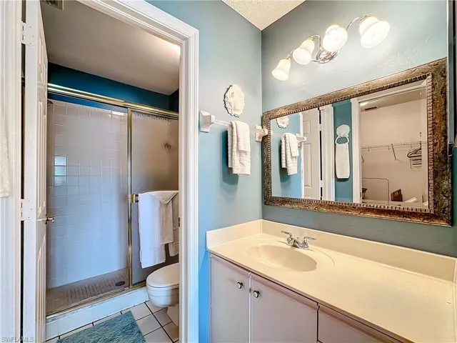 Bathroom featuring tile flooring, a textured ceiling, an enclosed shower, large vanity, and toilet