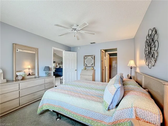 Bedroom with ceiling fan, carpet floors, and a textured ceiling