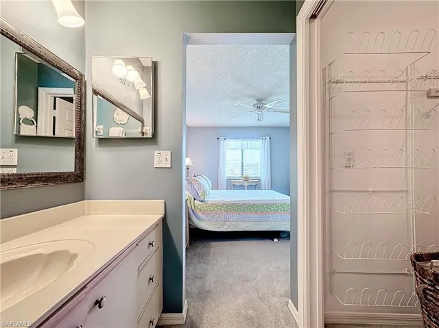Bathroom with a textured ceiling, ceiling fan, and oversized vanity