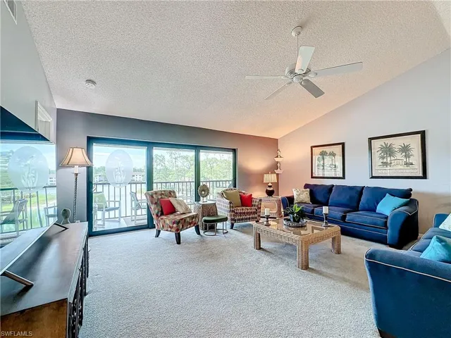 Living room with lofted ceiling, a textured ceiling, carpet flooring, and ceiling fan