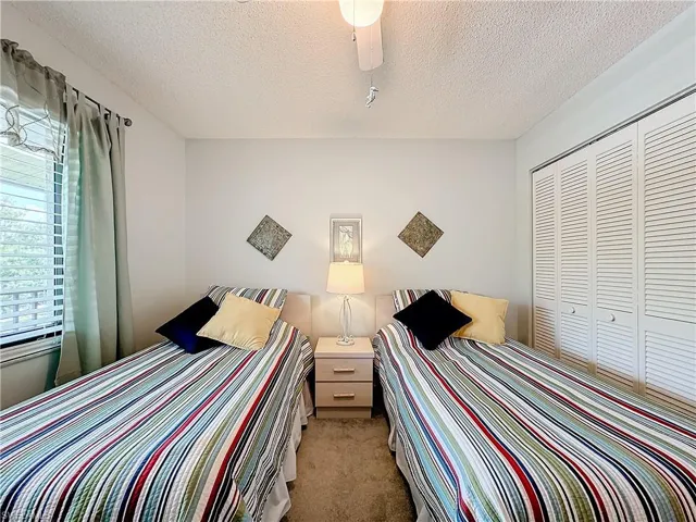 Unfurnished bedroom with light colored carpet, a closet, ceiling fan, and a textured ceiling