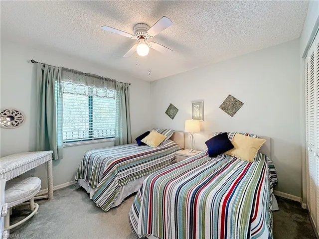 Bedroom with a closet, ceiling fan, carpet floors, and a textured ceiling