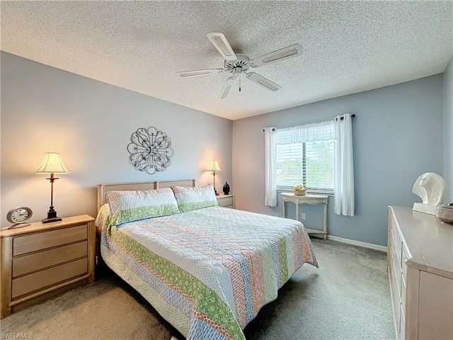 Carpeted bedroom with a textured ceiling and ceiling fan