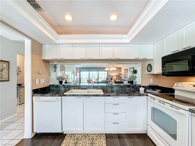 Kitchen featuring white cabinets, sink, ornamental molding, and white appliances
