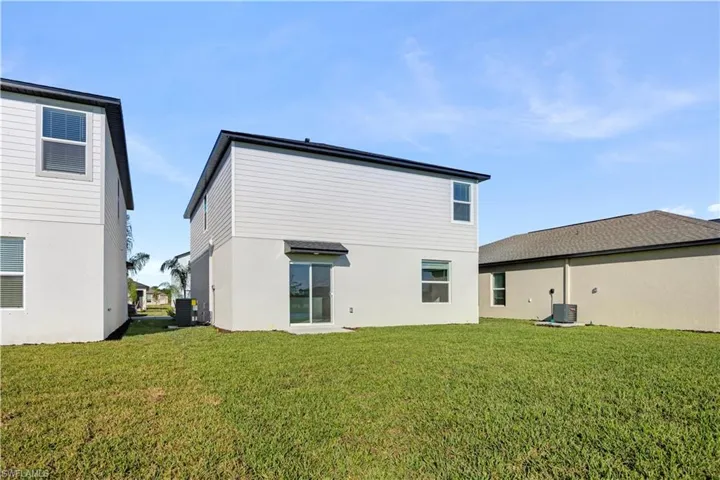 Rear view of house with a lawn and stucco siding