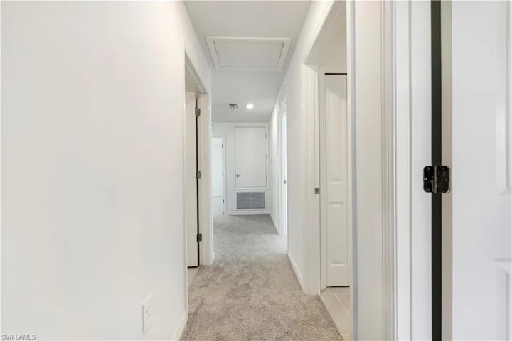 Hallway with light colored carpet and attic access