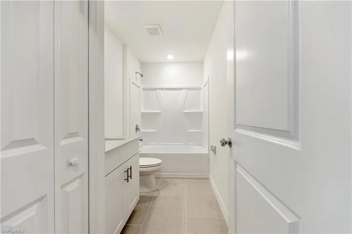 Bathroom with bathtub / shower combination, light tile patterned floors, a closet, and vanity