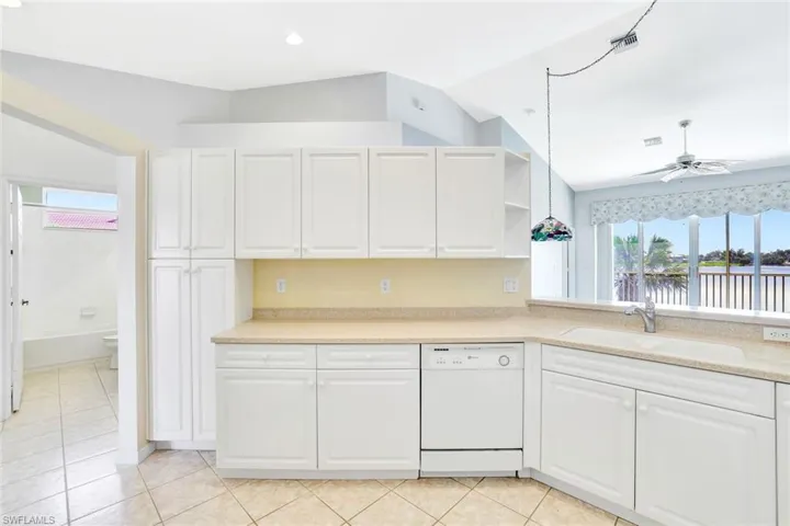 Kitchen featuring light countertops, white cabinets, dishwasher, and a sink
