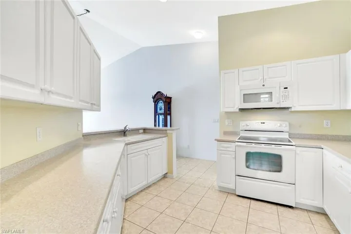 Kitchen featuring light countertops, white appliances, white cabinetry, and a sink