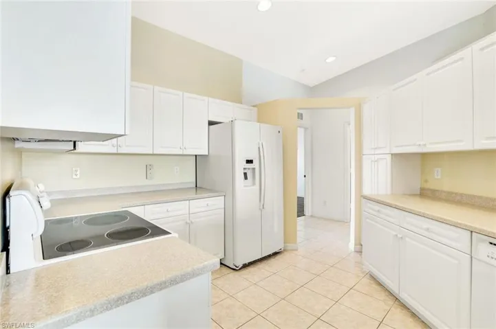 Kitchen with light countertops, white appliances, and white cabinets
