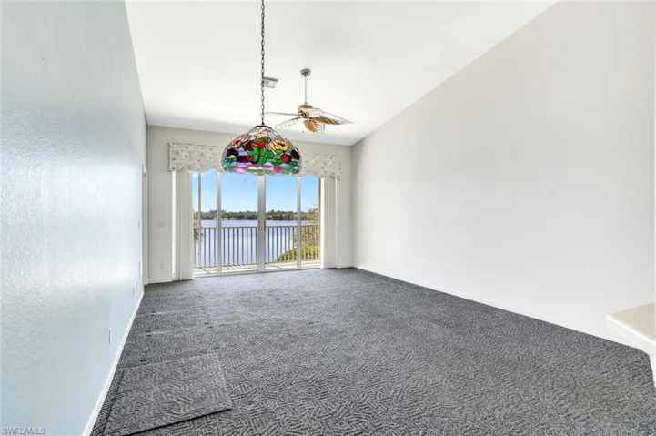 Empty room with visible vents, baseboards, ceiling fan, a water view, and carpet