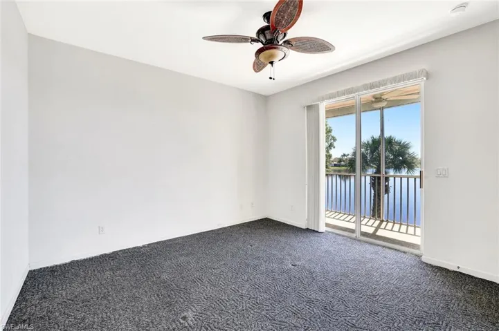 Empty room featuring ceiling fan, dark carpet, and baseboards