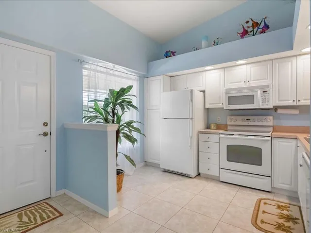 Kitchen featuring white appliances, white cabinetry, light countertops, and light tile patterned flooring