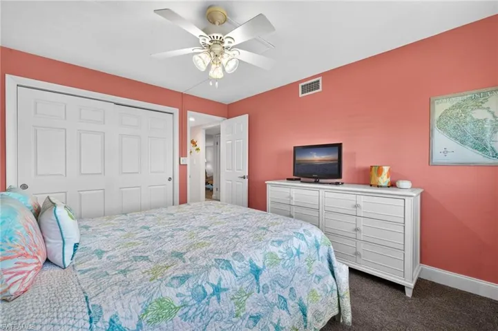Bedroom with dark colored carpet, a ceiling fan, and a closet
